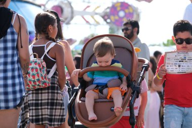 Eğlence parkındaki yetişkinler ve çocuklar salıncakta sallanıyorlar. İnsanlar bilet alırlar aileleriyle vakit geçirirler. Kanada Vancouver 2023 şapkalı Kanadalı büyük bir kalabalık tatilde.