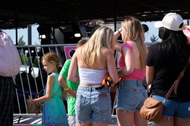 Eğlence parkındaki yetişkinler ve çocuklar salıncakta sallanıyorlar. İnsanlar bilet alırlar aileleriyle vakit geçirirler. Kanada Vancouver 2023 şapkalı Kanadalı büyük bir kalabalık tatilde.