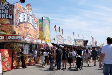 Eğlence parkındaki yetişkinler ve çocuklar salıncakta sallanıyorlar. İnsanlar bilet alırlar aileleriyle vakit geçirirler. Kanada Vancouver 2023 şapkalı Kanadalı büyük bir kalabalık tatilde.