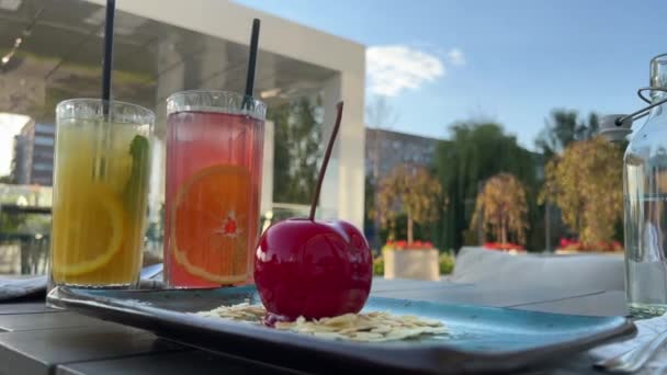 柠檬饮料和橙子饮料在夏天的阳台上 靠近美味的慕斯甜点 在杏叶上有一个巨大的叶柄 在外面吃早餐 花时间在一起 — 图库视频影像