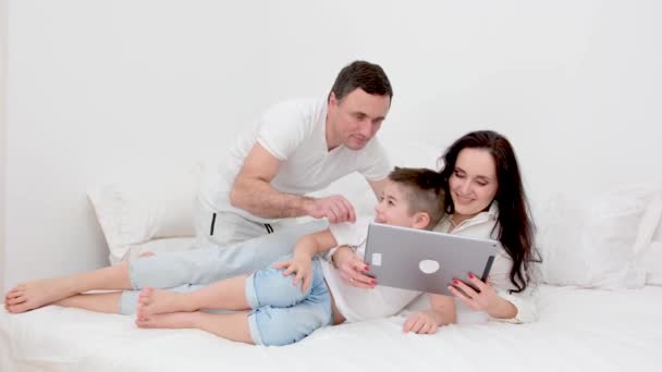Família Cama Branca Com Tablet Examinando Jogo Pai Mostrando Como — Vídeo de Stock