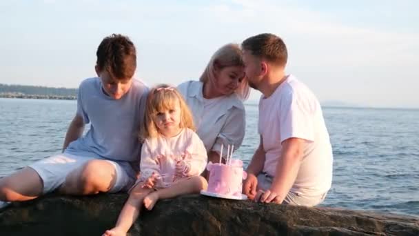 4人の家族が一緒に座って 夏休みのビーチで海を見ています 高品質の4K映像 — ストック動画
