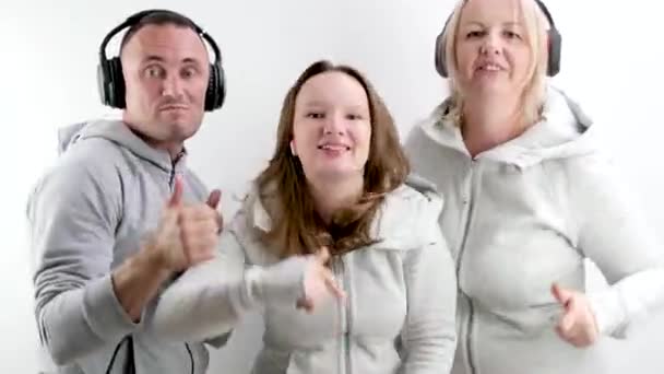 ホワイトウォールショークラスの背景とのダンス ヘッドフォンに置かれた親指 音楽を聞く人々 陽気な家族の幸せなグループの人々 — ストック動画