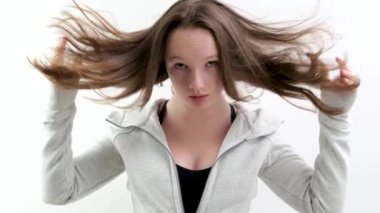 İyi bakımlı kahverengi saçlı güzel bir genç kız beyaz arka plan stüdyosunda başını yavaş çekimde sallıyor ceketini yan gülüşüne göre ayarlıyor. Şefkat güzelliği