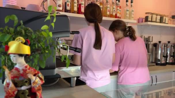 ピンクの服に2人の女の子を準備するドリンク付きのカフェは ボール居心地の良いカフェコーヒーマシンで美味しいバブルティーを準備します イースタンスタイル — ストック動画
