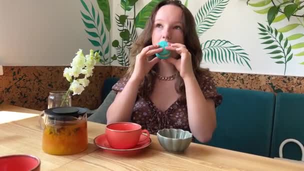Ein Junges Mädchen Beißt Einen Macaron Während Sie Einem Tisch — Stockvideo
