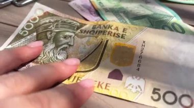 Masadaki 1.000 ve 5 bin banknotluk Arnavut para banknotları, bir restoranda çok renkli para ödemelerine bakan bir kadının elleri düzeltiyor. para faturası