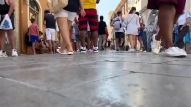 Şehirdeki Corfu merkez caddesinde yürüyen turist kalabalığının bacakları yerdeki kaldırımlı fayanslar tanınmaz haldeki turistlerin mesaj yollamak için yer açması. Yunanistan