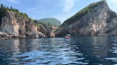 Korfu adası yakınlarındaki tekne turu temiz su dağlarının derinliklerinde doğal bahar mevsiminde kayıkçıları geçiyor. turistler ve gezginler