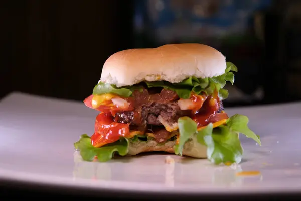 Video overhead shot of bitten burger in bun on white plate with copy space. tasty hot homemade fast food meal. High quality 4k footage