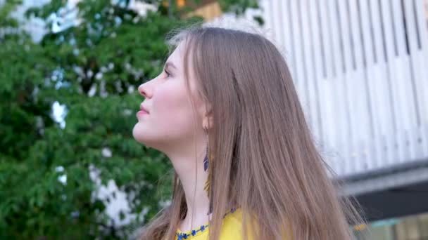 若い美しい女性 黄色の大都市の若い少女は 刺繍されたブラウス 長い茶色の髪 笑顔の羽のイヤリング 服の黄色と青の色 ウクライナの民族衣装 — ストック動画