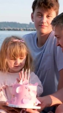 Deniz kıyısında küçük kızların doğum günlerini kutlayan mutlu bir aile. Anne, baba, anne ve kız kardeşin okyanus kıyısında hediyelerini açıyor. Güneşli bir günde