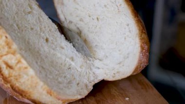Tam tahıllı ekmek mutfak ahşap tabağına konmuş ve şefin elinde altın bıçak var. Masanın üzerinde taze ekmek var. Mutfak masasında taze ekmek sağlıklı beslenme ve geleneksel fırın konsepti