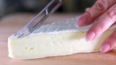 Tahta kesme tahtasındaki İtalyan peynirinin kompozisyonu. Bir el bıçağı alır ve kalitesinin tadını çıkarmak için birkaç parça kırar. Yüksek kalite 4k görüntü