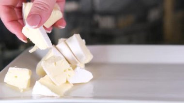 Tahta kesme tahtasındaki İtalyan peynirinin kompozisyonu. Bir el bıçağı alır ve kalitesinin tadını çıkarmak için birkaç parça kırar. Yüksek kalite 4k görüntü