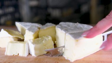 Tahta kesme tahtasındaki İtalyan peynirinin kompozisyonu. Bir el bıçağı alır ve kalitesinin tadını çıkarmak için birkaç parça kırar. Yüksek kalite 4k görüntü