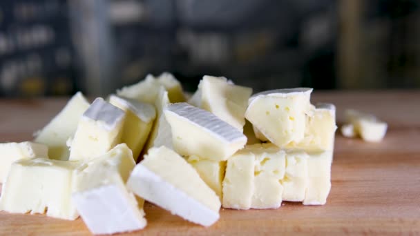 木製の切断板にイタリアのチーズの構成 片手はナイフを取り 品質を味わうためにいくつかのピースを壊します 高品質の4K映像 — ストック動画
