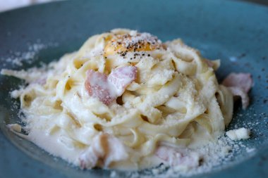 Makarnayı bir tabaktan carbonara sosuyla alan çatala yakın çekim. Çatallı sıcak spagetti. İtalyan mutfağı ve ev yemeği konsepti. Yüksek kalite 4k görüntü