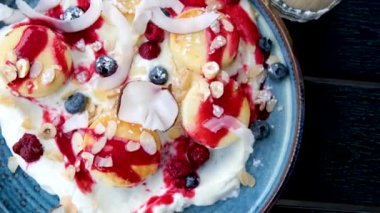 Çilek reçelli, taze çilekli, ekşi kremalı Rus tatlı cheesecakes şurubu üzerine düşen yabanmersini. Yavaş çekim dikey video. Yüksek kalite 4k görüntü