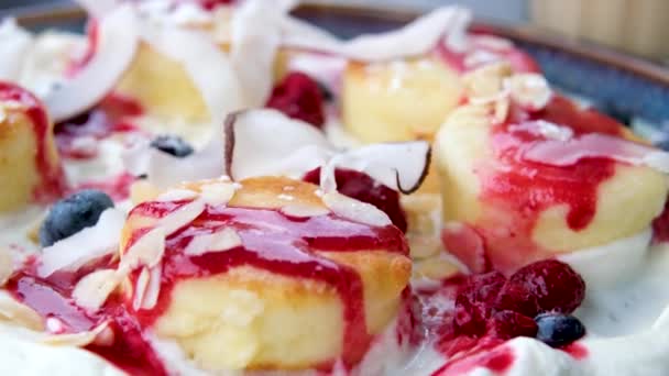 在俄罗斯甜甜的甜食芝士蛋糕糖浆与浆果果酱 新鲜草莓 酸奶油的一道菜上掉下蓝莓 慢动作垂直视频 高质量的4K镜头 — 图库视频影像
