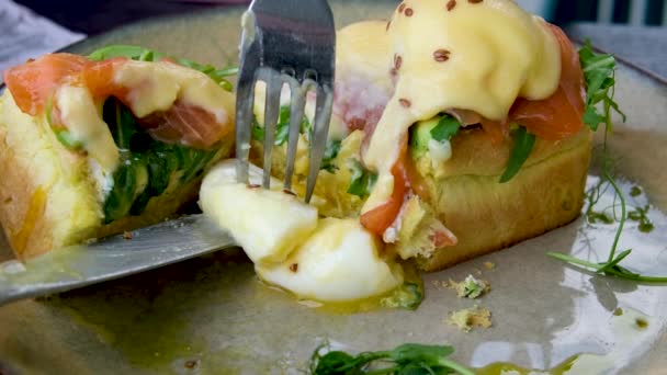 パンのトースト 密猟された卵 アボカドパルプ エンドウ豆のミクログリーンとカフェのプレート上の新鮮な野菜 クローズアップ 朝食時間 高品質の4K映像 — ストック動画