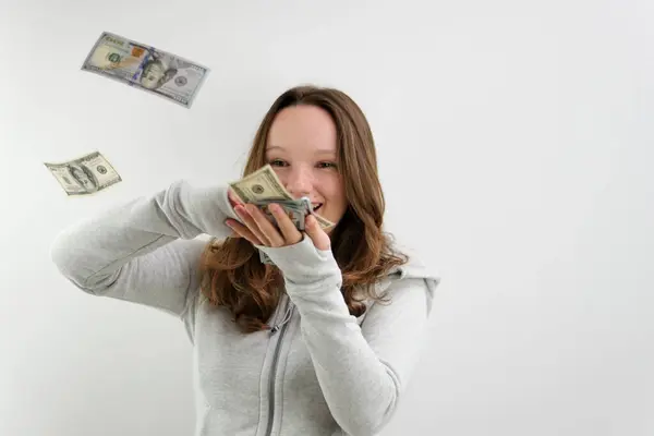 stock image young woman with a calm face counts out 100 dollar bills on a white background beautiful well-groomed hair money for beauty beauty salon buy pay. old and new banknotes