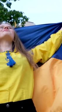 İşlemeli sarı gömlekli güzel bir Ukraynalı kadın mavi işlemeli Ukrayna bayrağı taşıyor. Evin arka planında zafer hayali kuran bir ağaç yardım istiyor üzgün gözler sarı saçlar