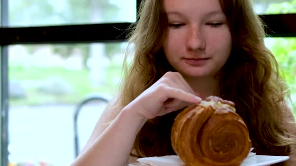 Ένα Νεαρό Κορίτσι Τρώει Ένα Στρογγυλό Κρουασάν Ένα Εστιατόριο Δίπλα — Αρχείο Βίντεο