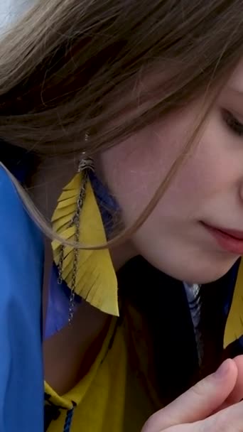乌克兰年轻漂亮的姑娘站着 双手为乌克兰国旗包裹的胜利战争祈祷 — 图库视频影像