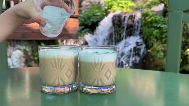 Přidat Kostky Ledu Skleněných Sklenic Cappuccino Pozadí Vodopádu Albánii Cestovní — Stock video