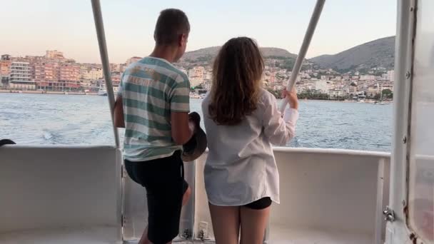 阿尔巴尼亚男孩女孩坐在游艇上旅行 观望着Ksamil市和Saranta Ionian海的风景 青少年们在度假时相互指责朋友 — 图库视频影像