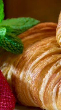 Beyaz tabakta güzel, şık bir video. İki kruvasan. Kocaman çilek ve nane şekeri. 