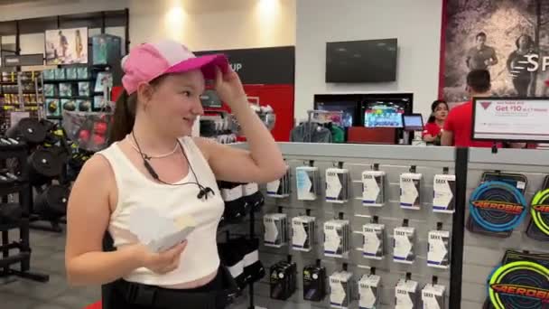 体育奇克在体育商店里买新东西 年轻的少女在结帐时选择运动用品中的帽子和鞋子 拿起购物 盒子和夏天 Surrey Canada 2023耳机 — 图库视频影像