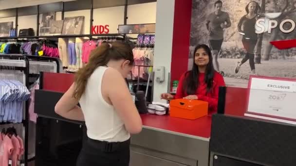 体育奇克在体育商店里买新东西 年轻的少女在结帐时选择运动用品中的帽子和鞋子 拿起购物 盒子和夏天 Surrey Canada 2023耳机 — 图库视频影像