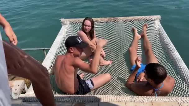 在爱奥尼亚海度假的青少年阿尔巴尼亚青少年朋友躺在河上的吊床上跳入水里去与一个女孩和四个男孩交流阿尔巴尼亚 — 图库视频影像
