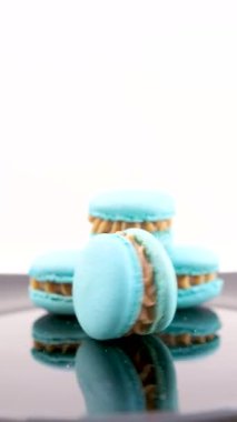 Bir kız gri arka planda fotoğraf çekmek için mavi ve pembe kurabiyeler seriyor. Gri arka planda makaronlar, renkli Fransız kurabiyeleri. Renkli badem kurabiyelerinden yapılmış yaratıcı bir düzen. Yiyecek.