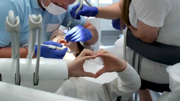 Νεαρή Κοπέλα Δείχνει Την Καρδιά Χέρια Καθισμένος Στο Οδοντιατρικό Γραφείο — Αρχείο Βίντεο