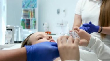 En son teknoloji temizliği ve diş beyazlatma hemşiresi ve doktor genç bir dişçinin dişlerini tedavi ediyor. Genç bir kızın maskeleri eldivenleri temizleme temizliği yapıyor. Klinikteki en son cihaz.