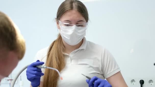 最新の技術クリーニングとホワイトニング歯科看護師と若い女性患者ティーンエイジャーマスクの歯を治療する医師は清潔な衛生を手袋します クリニックの歯科オフィスで最新のデバイス — ストック動画