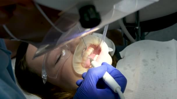 最新的技术是清洁和美白牙齿的护士和医生 治疗一名年轻女性患者的牙齿时 会戴上手套清洁卫生 诊所牙科诊所最新的设备 — 图库视频影像