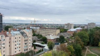 Ukrayna 'nın Vinnitsa kentindeki bir dönme dolaptan, parkın renkli sepetlerindeki uzun demir çark manzaralı yeşil ağaçlara ait bir video çekiyorum. Yağmurlu gökyüzü