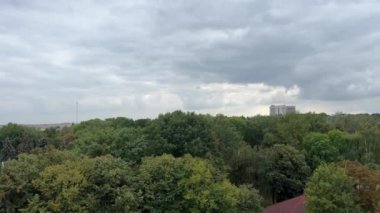 Ukrayna 'nın Vinnitsa kentindeki bir dönme dolaptan, parkın renkli sepetlerindeki uzun demir çark manzaralı yeşil ağaçlara ait bir video çekiyorum. Yağmurlu gökyüzü