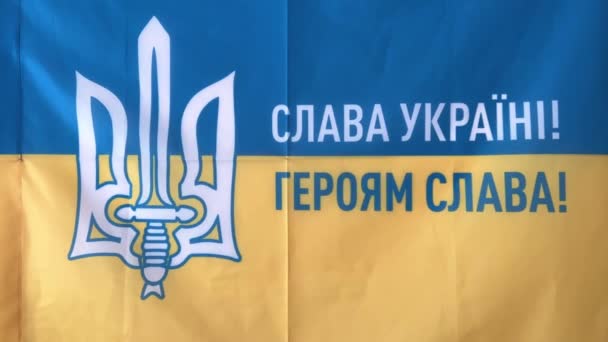乌克兰国旗上有一个三叉戟和剑题词 用乌克兰语写着 荣耀给乌克兰英雄的荣耀 墙上挂着黄色和蓝色的旗帜 — 图库视频影像