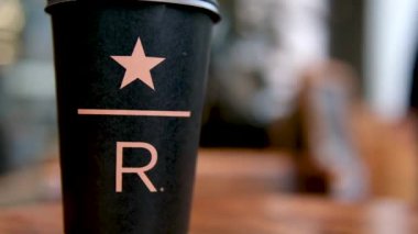 Starbucks Resort Black Starbucks bardağı. Kahve dükkanının masasının üzerinde büyük R harfinin altı çizili. Lezzetli yeni kahve lüksü. En yeni marka.