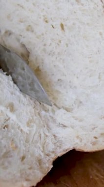 Tam tahıllı ekmek mutfak ahşap tabağına konmuş ve şefin elinde altın bıçak var. Masanın üzerinde taze ekmek var. Mutfak masasında taze ekmek sağlıklı beslenme ve geleneksel fırın konsepti