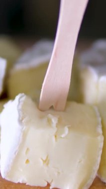 Tahta kesme tahtasındaki İtalyan peynirinin kompozisyonu. Bir el bıçağı alır ve kalitesinin tadını çıkarmak için birkaç parça kırar. Yüksek kalite 4k görüntü dikey video