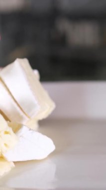 Tahta kesme tahtasındaki İtalyan peynirinin kompozisyonu. Bir el bıçağı alır ve kalitesinin tadını çıkarmak için birkaç parça kırar. Yüksek kalite 4k görüntü