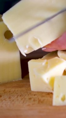 Tahta bir kesme tahtasının üzerinde bıçakla peynir kesen kadın elleri. Yüksek kalite 4k görüntü dikey video