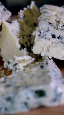 Siyah tabakta rotasyon peyniri. Arka plandaki kesme tahtasındaki Dorblu peyniri. Yüksek kalite 4k görüntü dikey video