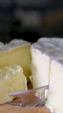 Tahta kesme tahtasındaki İtalyan peynirinin kompozisyonu. Bir el bıçağı alır ve kalitesinin tadını çıkarmak için birkaç parça kırar. Yüksek kalite 4k görüntü dikey video